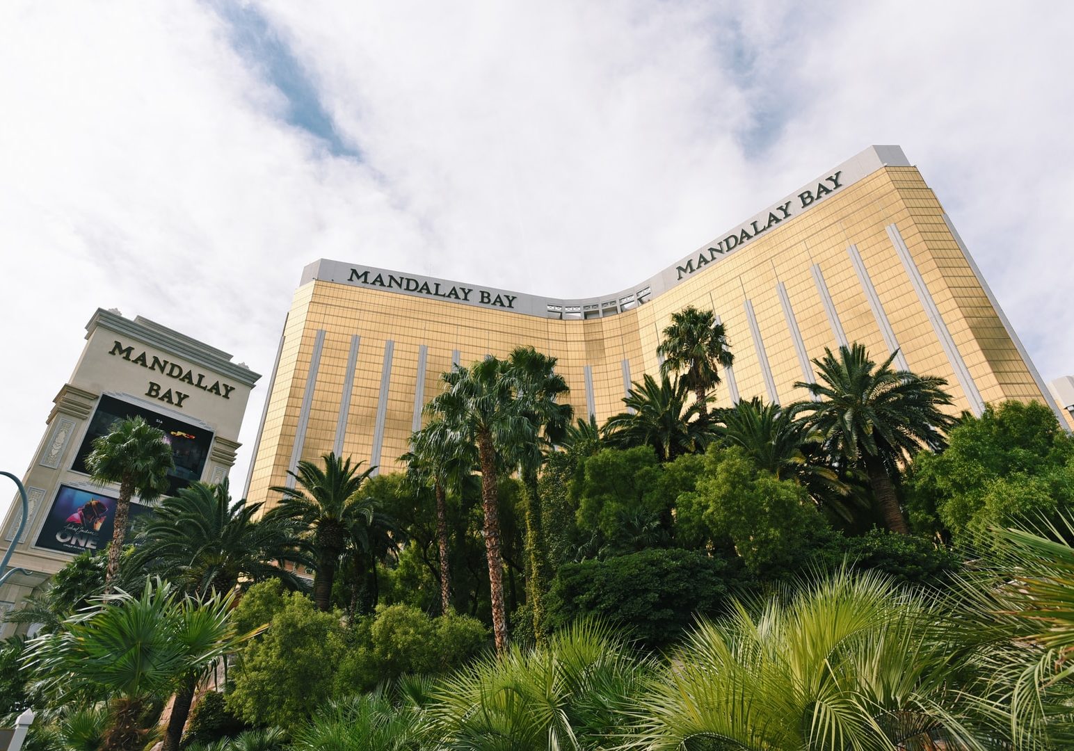 brown concrete building near green trees under white clouds during daytime